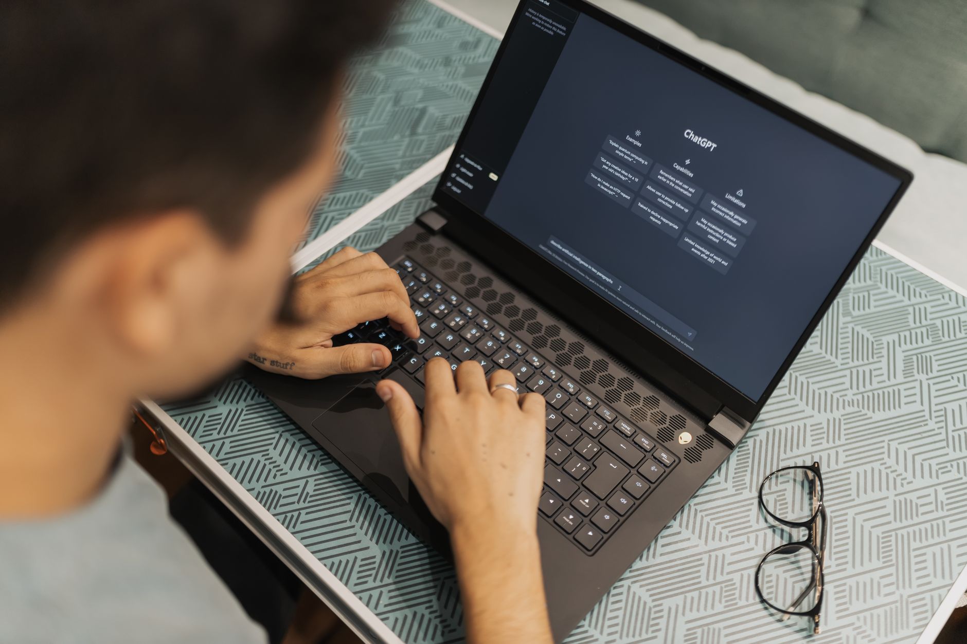 A person typing a prompt into an AI assistant on a laptop while social media icons are displayed on screen
