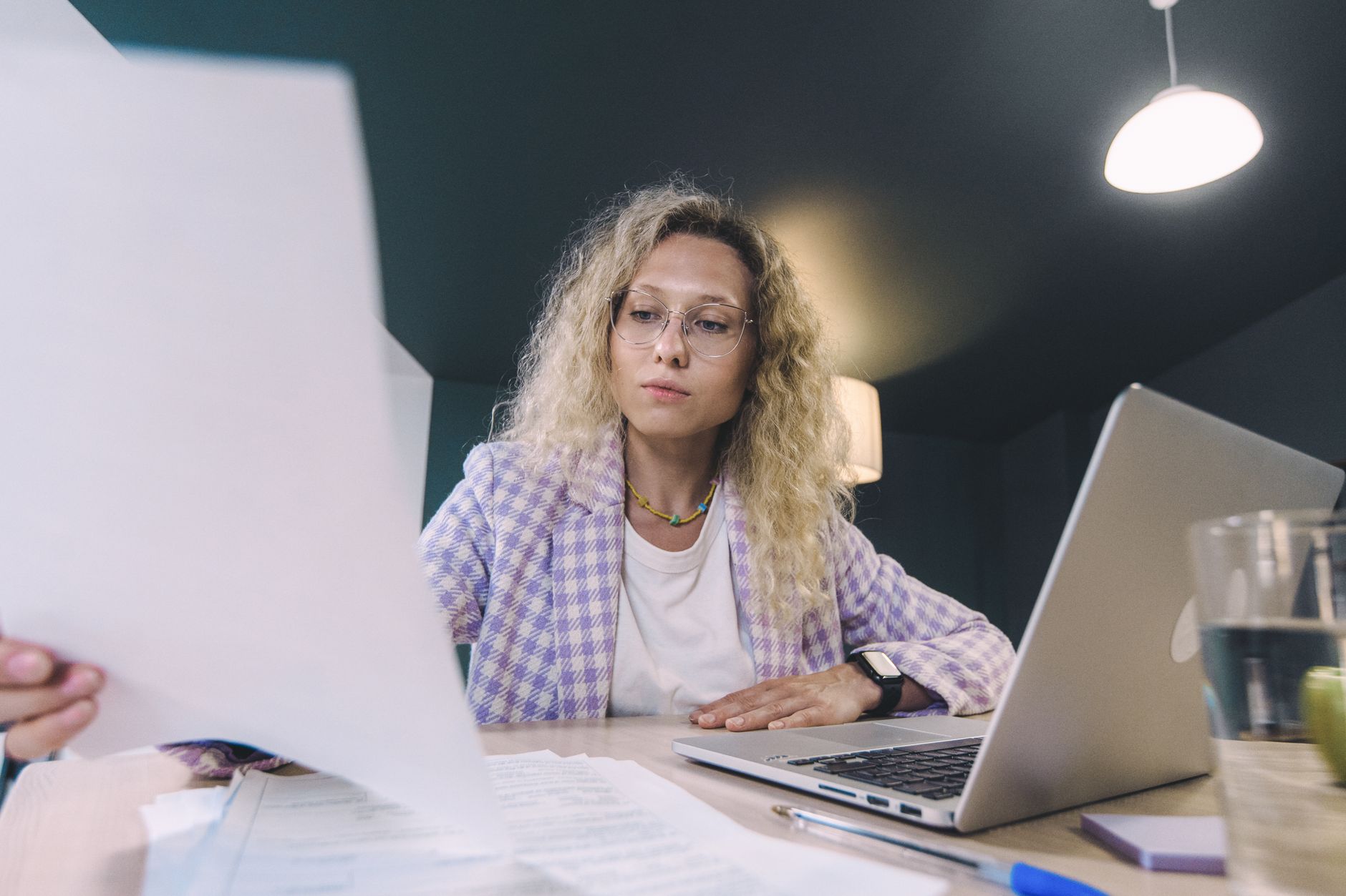 A freelancer reviews a digital invoice on a laptop at a tidy desk with a coffee cup and notebook nearby.