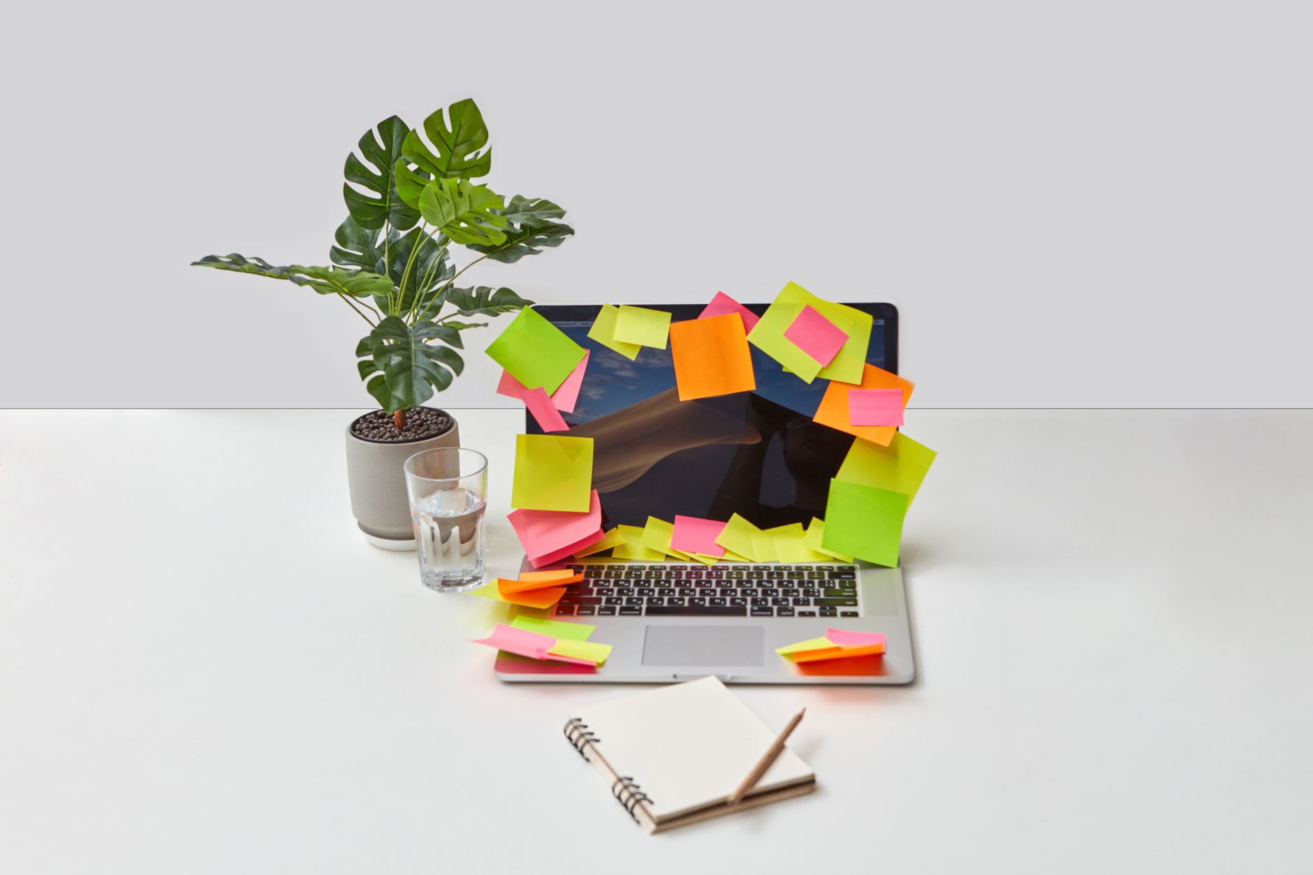 A person connects automation steps on a laptop while colorful sticky notes cover a wall nearby.